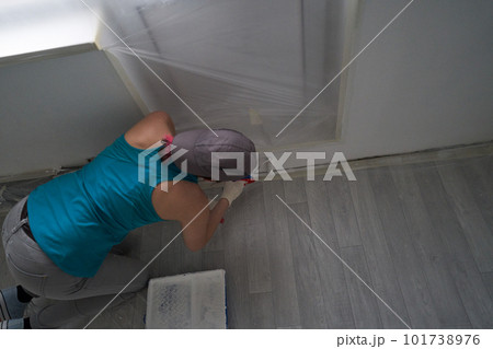 Woman paints the wall with a roller 101738976
