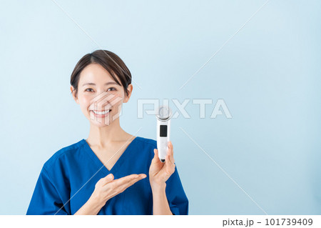 美顔器の説明をするスクラブを着たミドル女性 美顔器の説明をするスクラブを着たミドル女性 101739409