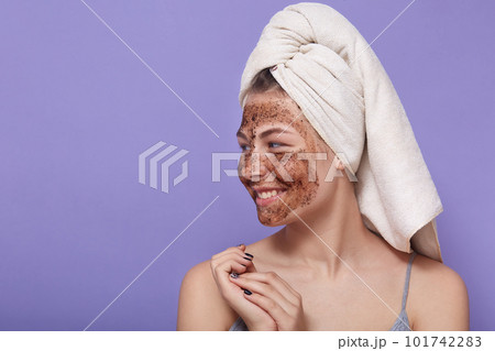 Image of adorable attractive cute young female looking aside, having pleasant facial expression, having white towel on head, being in good mood, applying face mask. Copyspace for advertisement. Image of adorable attractive cute young female looking aside, having pleasant facial expression, having white towel on head, being in good mood, applying face mask. Copyspace for advertisement. 101742283