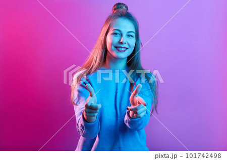 Winsome lady standing isolated over pink neon background and pointing directly to camera with her index finger finger, expressing happiness, being in good mood. Winsome lady standing isolated over pink neon background and pointing directly to camera with her index finger finger, expressing happiness, being in good mood. 101742498