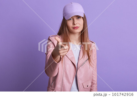 Image of confident arrogant female making gesture, raising arm, pointing at camera with forefinger, wearing street style clothes, showing direction, having long hair. Youth and emotions concept. Image of confident arrogant female making gesture, raising arm, pointing at camera with forefinger, wearing street style clothes, showing direction, having long hair. Youth and emotions concept. 101742916