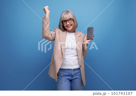 mature woman in a stylish bow chatting on the Internet in a smartphone on a studio background with mature woman in a stylish bow chatting on the Internet in a smartphone on a studio background with 101743107