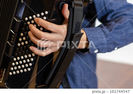 クロマチックボタン式アコーディオンを弾いている男性の手元 101744547