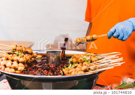 Food vendor hand holding pork meatballs in skewer with sweet chili sauce. 101744810