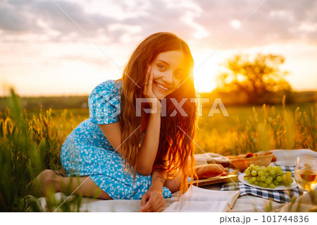 Young woman sits on a plaid with a book. Summer picnic in nature. Healthy food. Young woman sits on a plaid with a book. Summer picnic in nature. Healthy food. 101744836