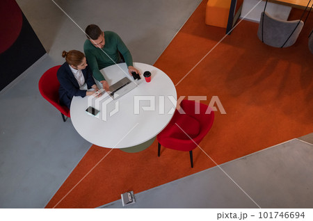 Top view of man and woman working on laptop at round table. Top view of man and woman working on laptop at round table. 101746694