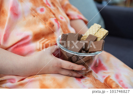 Close up of fat woman holding bowl chocolate sitting on sofa Close up of fat woman holding bowl chocolate sitting on sofa 101746827