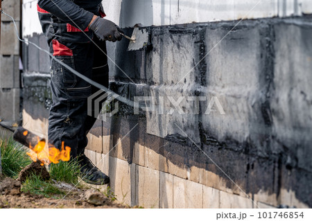 waterproofing of the wall with a covered asphalt belt during the construction of the house waterproofing of the wall with a covered asphalt belt during the construction of the house 101746854