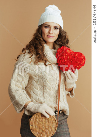happy elegant woman in beige sweater, mittens and hat 101747344