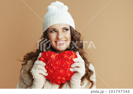 smiling woman in beige sweater, mittens and hat on beige smiling woman in beige sweater, mittens and hat on beige 101747348