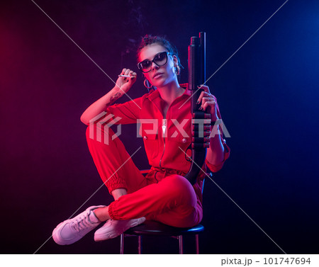 sexy bully girl smokes a cigarette with a shotgun on a dark background in neon light and a haze of copy paste 101747694