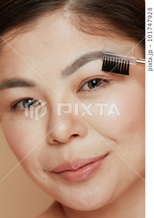 young woman with brow brush isolated on beige background 101747928