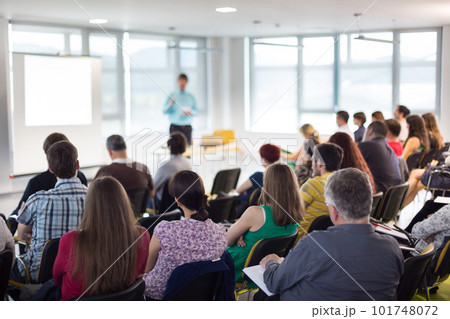 Business and entrepreneurship symposium. Speaker giving a talk at business meeting. Audience in conference hall. Rear view of unrecognized participant in audience. Business and entrepreneurship symposium. Speaker giving a talk at business meeting. Audience in conference hall. Rear view of unrecognized participant in audience. 101748072