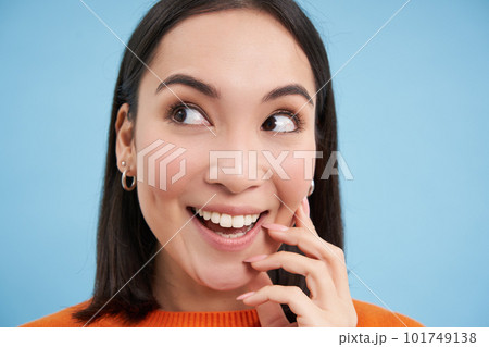 Beauty and wellbeing. Close up portrait of young happy asian woman, smiling and showing candid emotions, standing over blue background 101749138