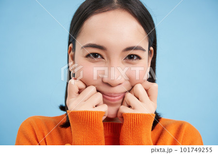 Beauty and wellbeing. Close up portrait of young happy asian woman, smiling and showing candid emotions, standing over blue background Beauty and wellbeing. Close up portrait of young happy asian woman, smiling and showing candid emotions, standing over blue background 101749255