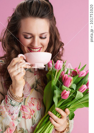 smiling stylish 40 years old woman in floral dress on pink 101751020