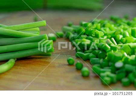 Cutting green garlic on wooden cutting board Cutting green garlic on wooden cutting board 101751205