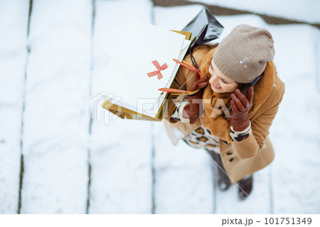 smiling woman in brown hat and scarf talking on phone 101751349