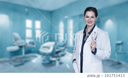 Doctor dentist woman with a tool in her hands stands . Doctor dentist woman with a tool in her hands stands . 101751413