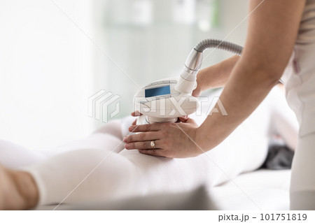 Cosmetics beautician holds LPG endermology device on body of a client lying on a cosmetics studio table Cosmetics beautician holds LPG endermology device on body of a client lying on a cosmetics studio table 101751819