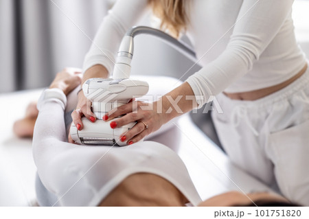 Female beautician holds LPG endermology device with both hands scanning the female body of her client Female beautician holds LPG endermology device with both hands scanning the female body of her client 101751820