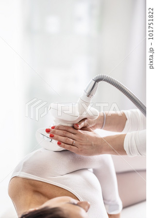 Woman in beautification studio lies on her side while cosmetician slides LPG endermology device through her body 101751822