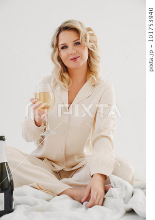 blonde in delicate pajamas in bed with a bottle and a glass of champagne blonde in delicate pajamas in bed with a bottle and a glass of champagne 101753940