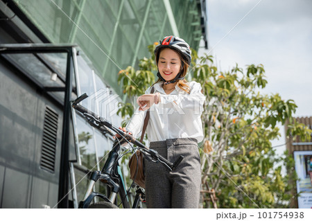 Portrait smiling woman check watch, Asian young businesswoman standing with bicycle checking time on modern buildings city street in morning before go to work at office, Business commuter, lifestyle 101754938