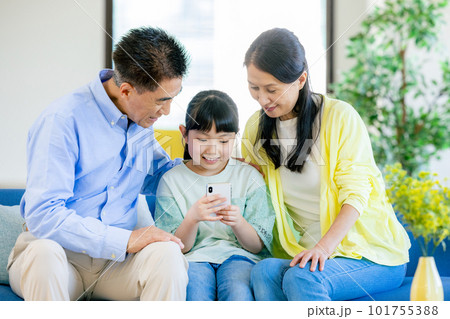 スマホを見る孫と祖父母 101755388