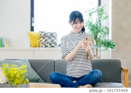 ソファーでスマホを操作する若い女性 ソファーでスマホを操作する若い女性 101755409