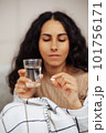 Beautiful young woman holding a pill and water 101756171