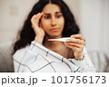 Anxious woman looking at thermometer. High temperature is always stressful for the body. 101756173
