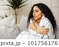 A beautiful young Arab woman escapes from the cold by wrapping herself in a blanket. The girl feels shivering and gets sick from the cold in the apartment. 101756176