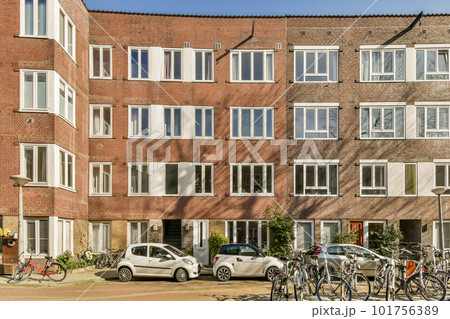 some bikes parked in front of an apartment building with many windows on the top and bottom part of the building some bikes parked in front of an apartment building with many windows on the top and bottom part of the building 101756389