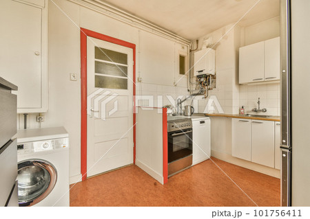 a small kitchen with an oven and dishwasher in the doord doorway leading to another room where there is a washing machine 101756411