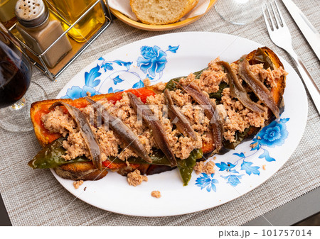 Toasted bread with chopped tuna, anchovies and baked bell pepper 101757014
