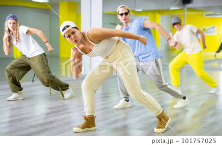 Teenage girl having group dance training in studio, performing dynamic elements 101757025