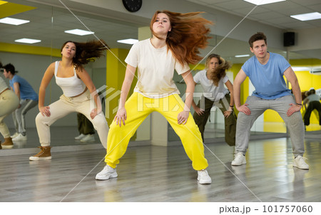Flexible and energetic male and female teenage dancers having fun during dance lesson together in spacious hall 101757060