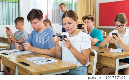 Pupils with smartphones sitting in class 101757106