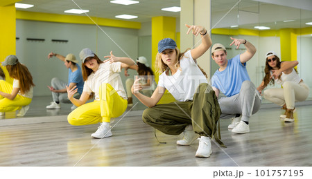 Active positive teenagers in casual wear performing dance elements during lesson in modern fitness studio Active positive teenagers in casual wear performing dance elements during lesson in modern fitness studio 101757195