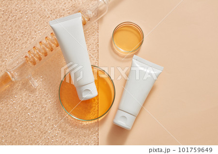 Laboratory concept with orange liquid contained inside of spiral pipe tube and glass petri dishes. Empty label white tubes for cosmetic product promotion Laboratory concept with orange liquid contained inside of spiral pipe tube and glass petri dishes. Empty label white tubes for cosmetic product promotion 101759649