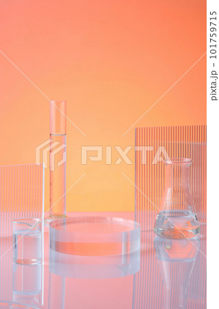 Front view of transparent podium with laboratory glassware filled colorless liquid and ribbed acrylic sheets on orange background. Blank space for display product. Science and medical background 101759715