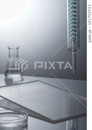 Laboratory glassware containing transparent solution and ribbed acrylic sheets decorated on back lit background. Science laboratory research and development concept 101759721