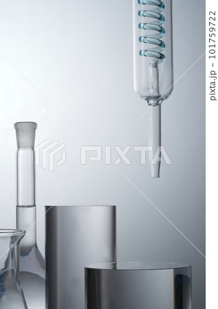 Closeup view of lab glassware filled transparent solution and cylinder podiums for cosmetic product presentation on light background. Concept: research, biochemistry, nature, pharmaceutical medicine 101759722