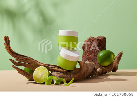 Unlabeled green jar are stacked on a big tree branch, a half of Lime and peels decorated. Beauty products extracted from Lime (Citrus aurantiifolia) can keep your skin firm and strong 101760059