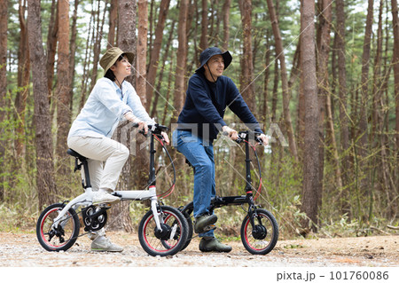 林間で電動自転車に乗るカップル 101760086