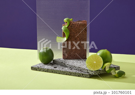 Platform for display cosmetic of lime extract with brick podiums, fresh limes and acrylic sheet on color background. Limes extract contains a lot of vitamin C and nutrients for effective skin care. 101760101