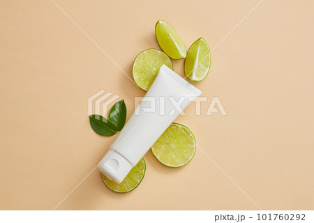 Unlabeled tube put on some Lime slices with leaves. Cosmetic product mockup extracted from Lime (Citrus aurantiifolia), it can enhance skin and hair condition 101760292