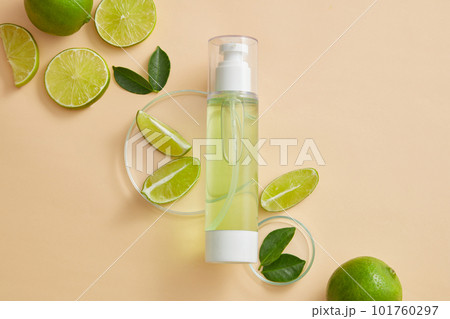 Empty label pump bottle dispenser displayed on beige background with petri dishes of Lime (Citrus aurantiifolia) slices and green leaves. Toner or serum cosmetic product promotion Empty label pump bottle dispenser displayed on beige background with petri dishes of Lime (Citrus aurantiifolia) slices and green leaves. Toner or serum cosmetic product promotion 101760297