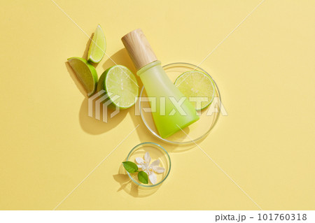 Unlabeled gradient jar with wooden cap placed on a glass petri dish with Lime slice over a pastel background. Mockup for beauty products of Lime (Citrus aurantiifolia) extract 101760318